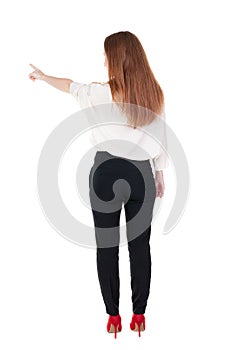 Back view of young redhead business woman pointing at wal