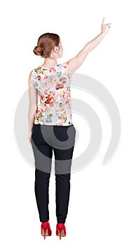 Back view of young redhead business woman pointing at wal