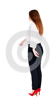 Back view of young redhead business woman pointing at wall.