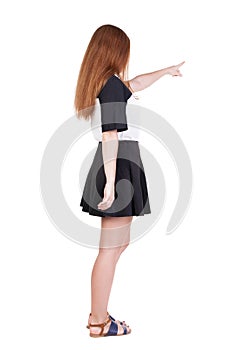 Back view of young redhead woman pointing at wall. beautiful gir