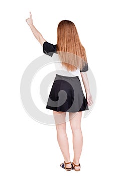 Back view of young redhead woman pointing at wall. beautiful gir