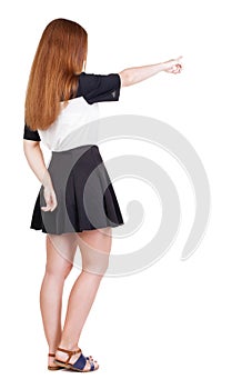 Back view of young redhead woman pointing at wall. beautiful gir