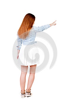 Back view of young redhead woman pointing at wall. beautiful gir