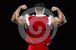 Back view of young Santa Claus showing off his strong biceps isolated on black background