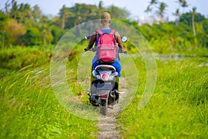 Back view of young tourist afro American black woman riding motorbike happy in beautiful Asia countryside along green rice fields