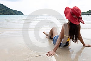 Back view of young woman on the beach looking at the sea