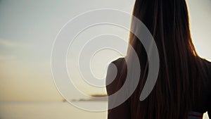 Back view of young woman at beach relaxing by the sea in summer.