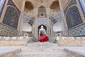 Back view of Young woman at Bukhara, Uzbekistan Mir-i-Arab Madrasa Kalyan minaret and tower.