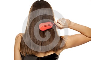 Back view of young woman combing her long hair