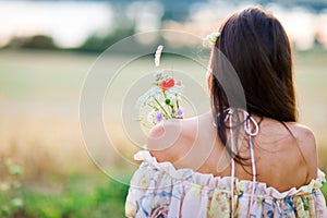 Back view of young woman dressed in summer dress have bouquet