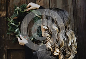 Back view of Young woman hanging a Christmas wreath on her home