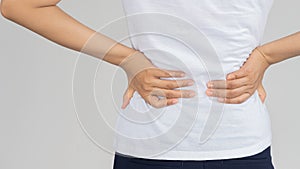 Back view of a young woman with lumbar pain standing on white background medical concept .