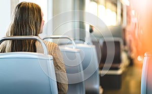 Back view of young woman sitting in public transportation