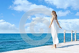 Back view of a young woman standing on a pier. Sea and sky back