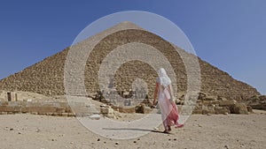 Back view of the young woman walking towards the Great Pyramids.