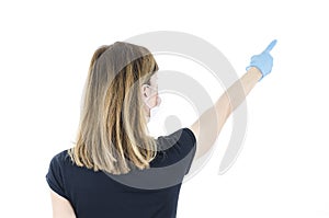 Back view of young woman with white face mask and blue gloves pointing finger up,