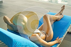 Back view of young women healthy body wearing white bikini and straw hat lifestyles relaxing near swimming pool sunbath, in the su