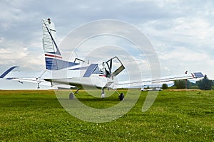 Back view of Zlin Z-43 four-seat airplane standing on a grass runway.