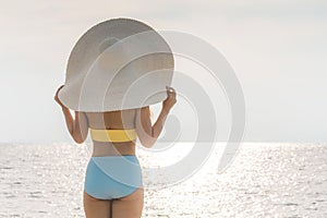 Back of views woman wearing yellow bikini enjoy with summer vacation on the beach feeling so happiness and cheerful