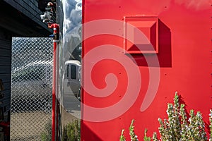 The back wall of a red metal food truck with a vent and gas supply line