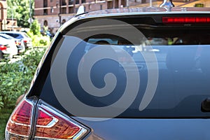 Back window of a car parked on the street in summer sunny day, rear view. Mock-up for sticker or decals