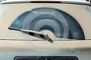 Back window covered with a dust layer of a dirty gray car.