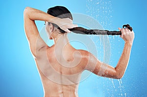Back of woman, shower and hair care in studio, blue background and hygiene routine. Female model cleaning head with