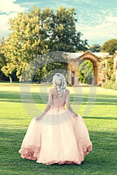 Back of woman wearing evening dress walking in formal garden