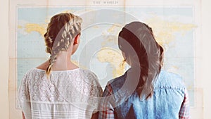 Back, women and world map on wall for travel, vacation and holiday destination choice. Rear view, people and geography