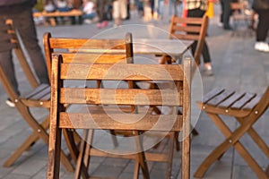 Back of wooden chair close up and table with chairs stands on street in city cafe