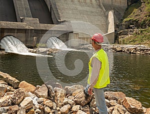 Back of worker in a helmet against the backdrop of hydroelectric turbines