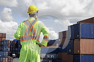 The back of worker man wearing safety clothing with helmet standing at logistic cargo containers shipping yard