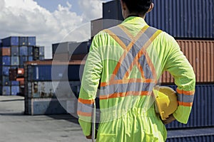 The back of worker man wearing safety clothing with helmet standing at logistic cargo containers shipping yard