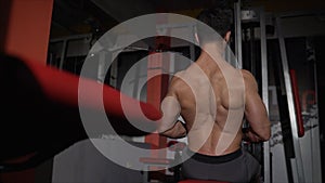 back workout in the gym. very power athletic guy bodybuilder, execute exercise with gym apparatus, on broadest muscle of