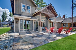 Back yard with fire pit and red chairs near newly bild luxury real estate home with forest biew and green grass