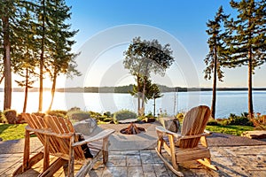 Back yard of waterfront house with adirondack chairs and fire pit photo