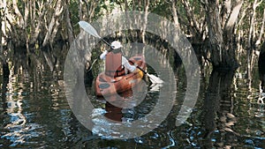 Back young adult woman paddling kayaking canoe on a lake on summer day