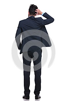 Back of a young business man scratching his head