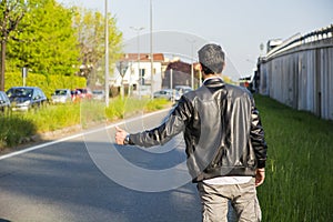 Back of young man, hitchhiker waiting on roadside