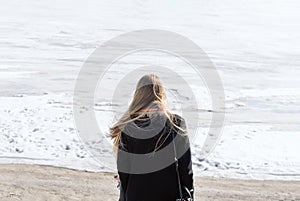Back of the young woman standing on the frozen river