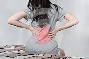 Backache and Lower back pain concept. Young woman suffering from back pain, on bed after waking up photo