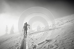 Backcountry skier pushing through the fog on a snowy slope