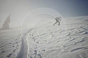 Backcountry skier pushing through the fog on a snowy slope