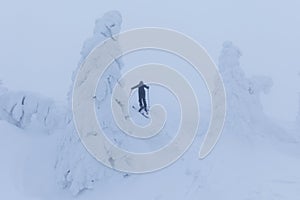 Backcountry skier pushing through the fog on a snowy slope. Ski touring in harsh winter conditions. Ski tourer sporting