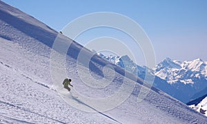 Backcountry skier skiing really fast down an untouched mountain side with loads of fresh powder snow