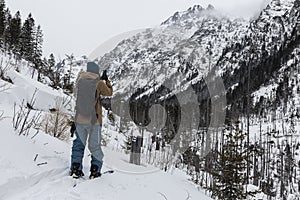 Backcountry skier takes pictures of snowy mountains in the fog