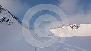 Backcountry skiers and mountain climbers stand near the summit cross of a high alpine moutnain peak in the Austrian Alps in deep w