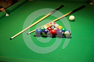 Backdrop of pyramid of pool balls and billiard cues on green billiard table