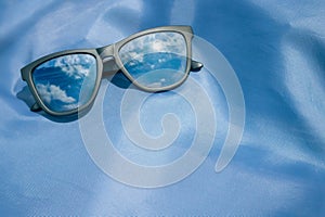 Backdrop of sunglasses reflecting the sky on a blue background