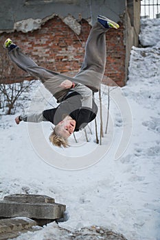 Backflip parkour in winter snow park - blonde hair teenager